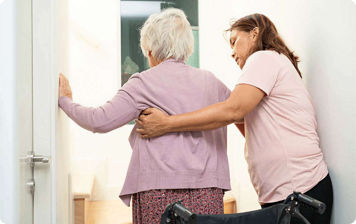 Caregiver supporting senior woman walking