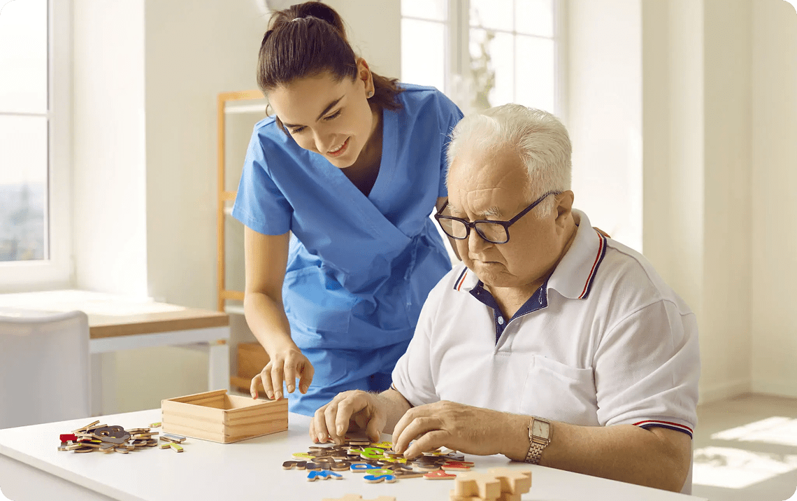 Elderly man solving puzzle with caregiver.