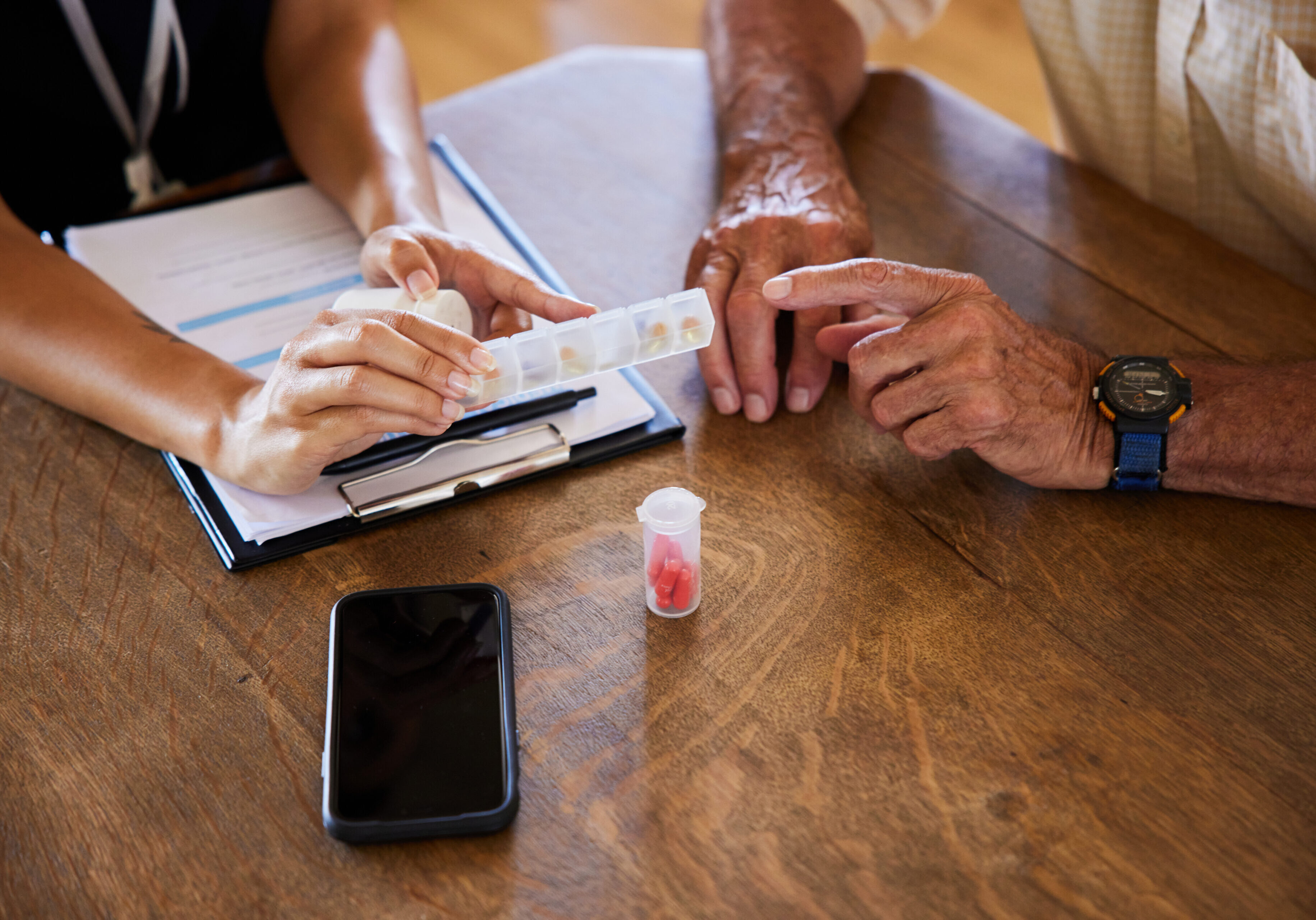 Close-up of a senior man discussing medication with a female healthcare worker at a table during a home visit